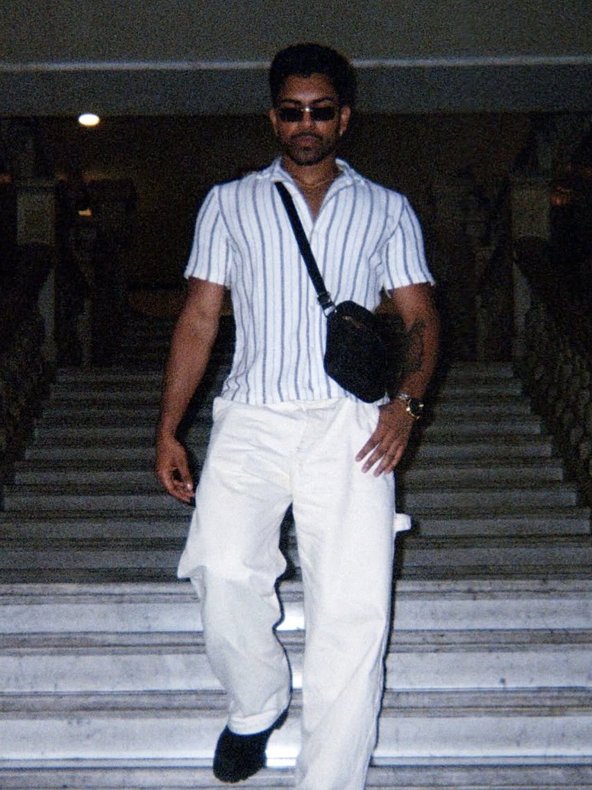 Striped shirt and white trousers walking down marble stairs